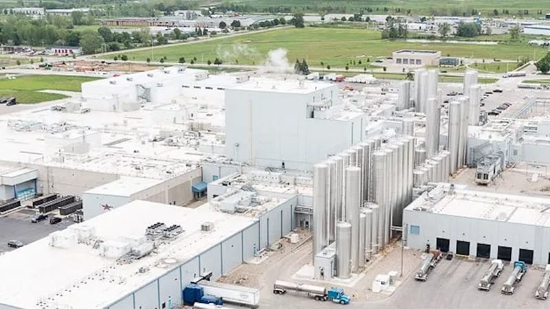 Aerial view of a large dairy production facility in Michigan with silos, tanker trucks, and surrounding farmland